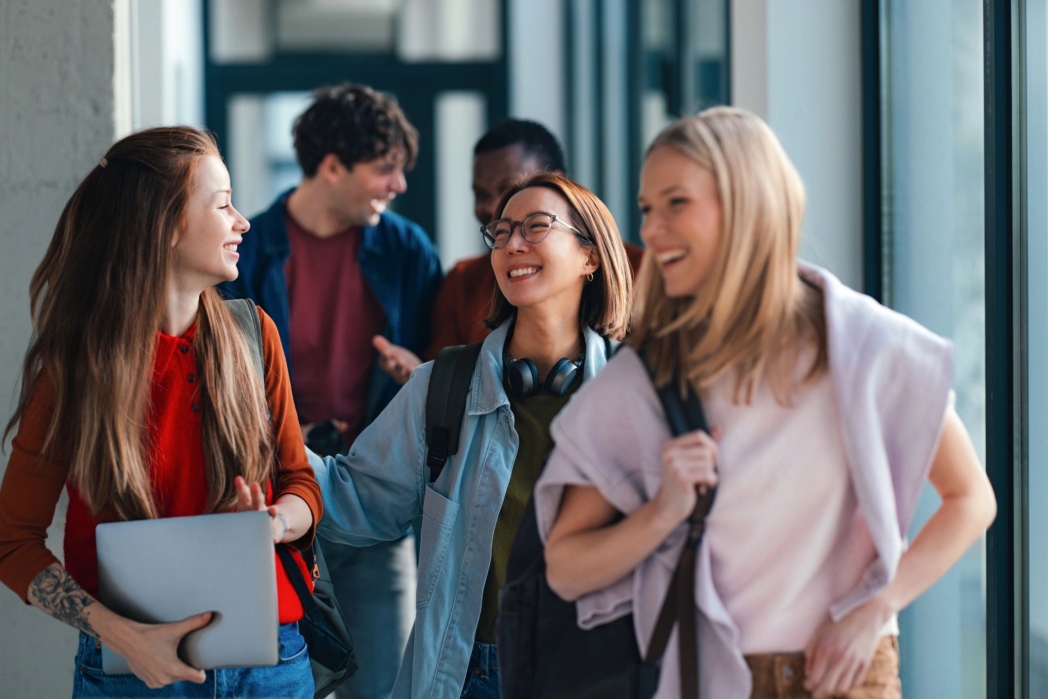 Happy university students walking together in a bright hallway
